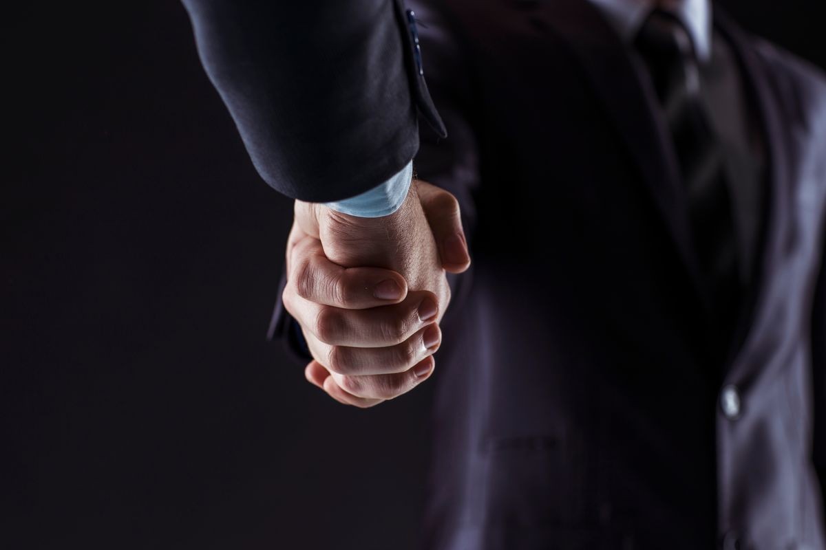 concept of a reliable partnership: a close-up of handshake of business partners on a black background.